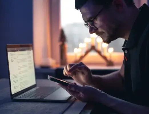 Mann arbeitet mit Laptop und Smartphone – mobile und Ladezeit Optimierung für flüssige Nutzererfahrung.