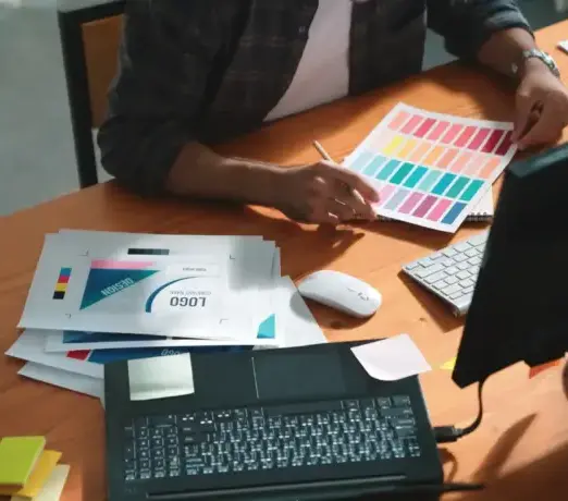 Designer arbeitet mit Farbmuster und Monitor – kreative individuelle Gestaltung von Webseiten.