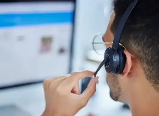 Support-Mitarbeiter mit Headset am Computer – Ansprechpartner für Webseiten-Wartung und Support.