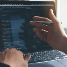 Hand zeigt auf Code am Monitor – gezielte Optimierungen beim Webseiten-Relaunch.
